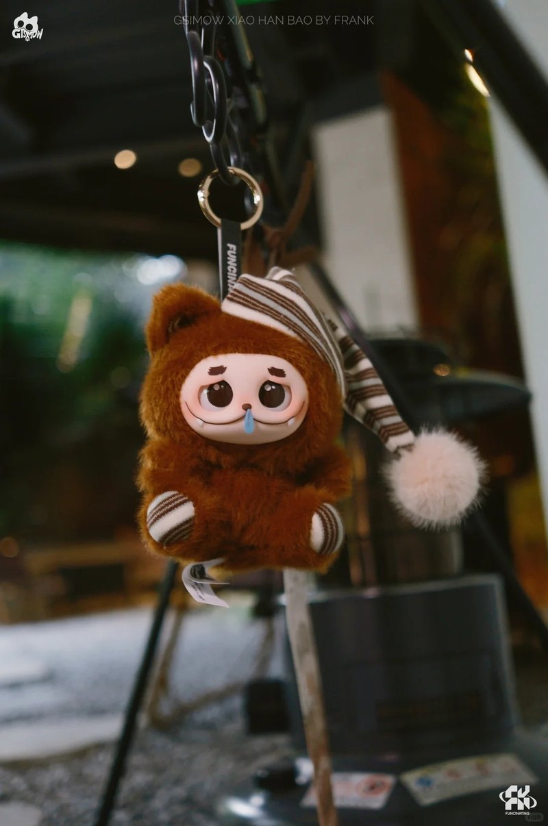 Single brown GISMOW plush charm in a striped nightcap clipped to a bag