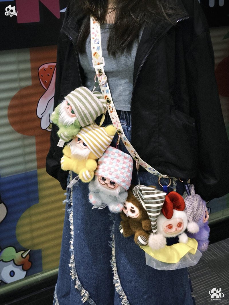 Several GISMOW plush charms clipped along a bag strap worn across the body